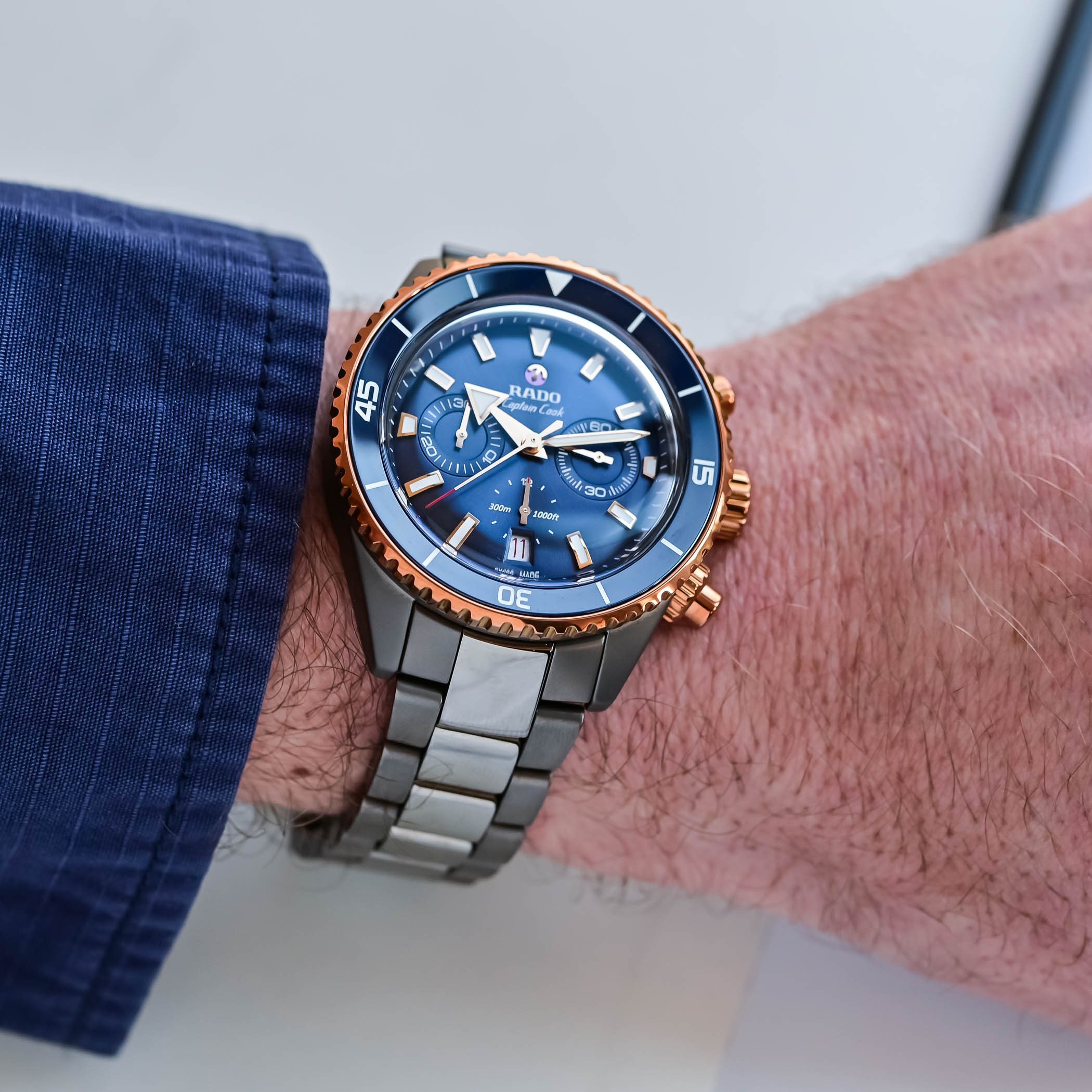 Rado Captain Cook High-Tech Ceramic Chronograph blue dial detail — rose-gold pivoting anchor, sunray blue sub-dials, red-tipped chronograph hands