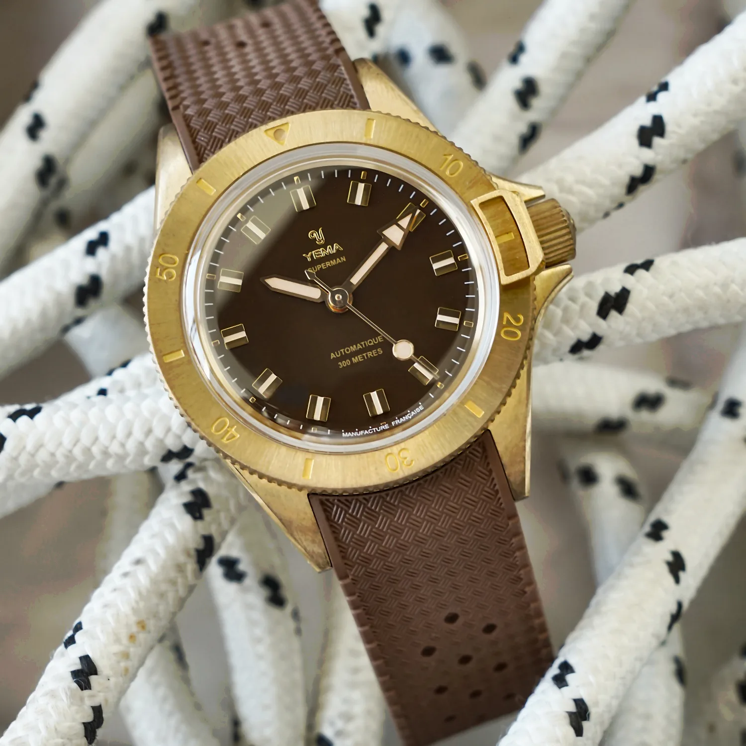 Yema Superman Bronze CMM.10 brown dial — warm brown glossy lacquered dial, gilt hour markers and bezel-lock mechanism visible alongside the bronze bezel