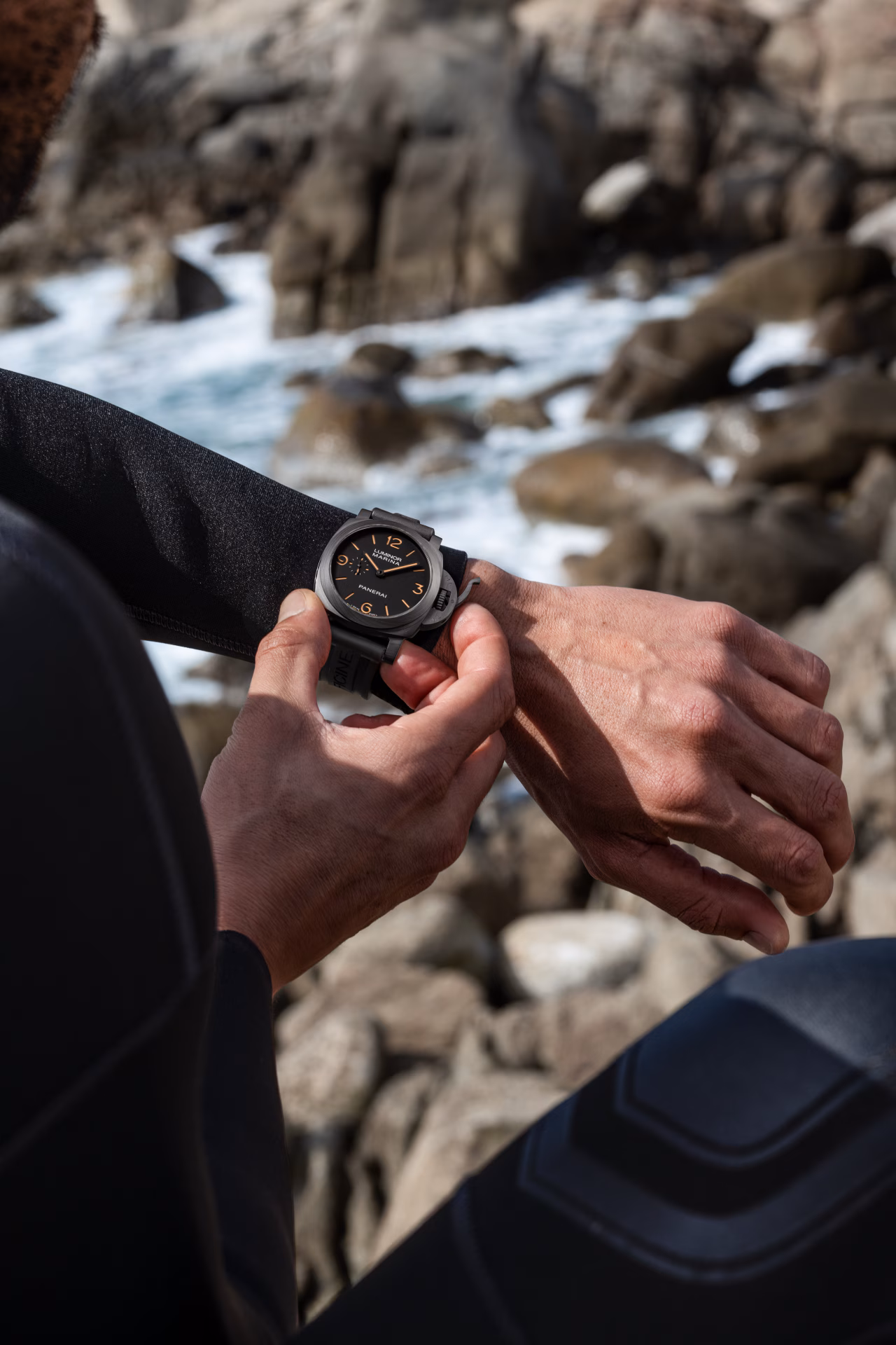 Panerai Luminor Marina PAM01707 worn on wrist by the ocean, diver adjusting the watch on a rocky coastline